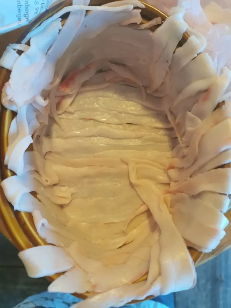 Eine Terrineform mit Speck ausgelegt