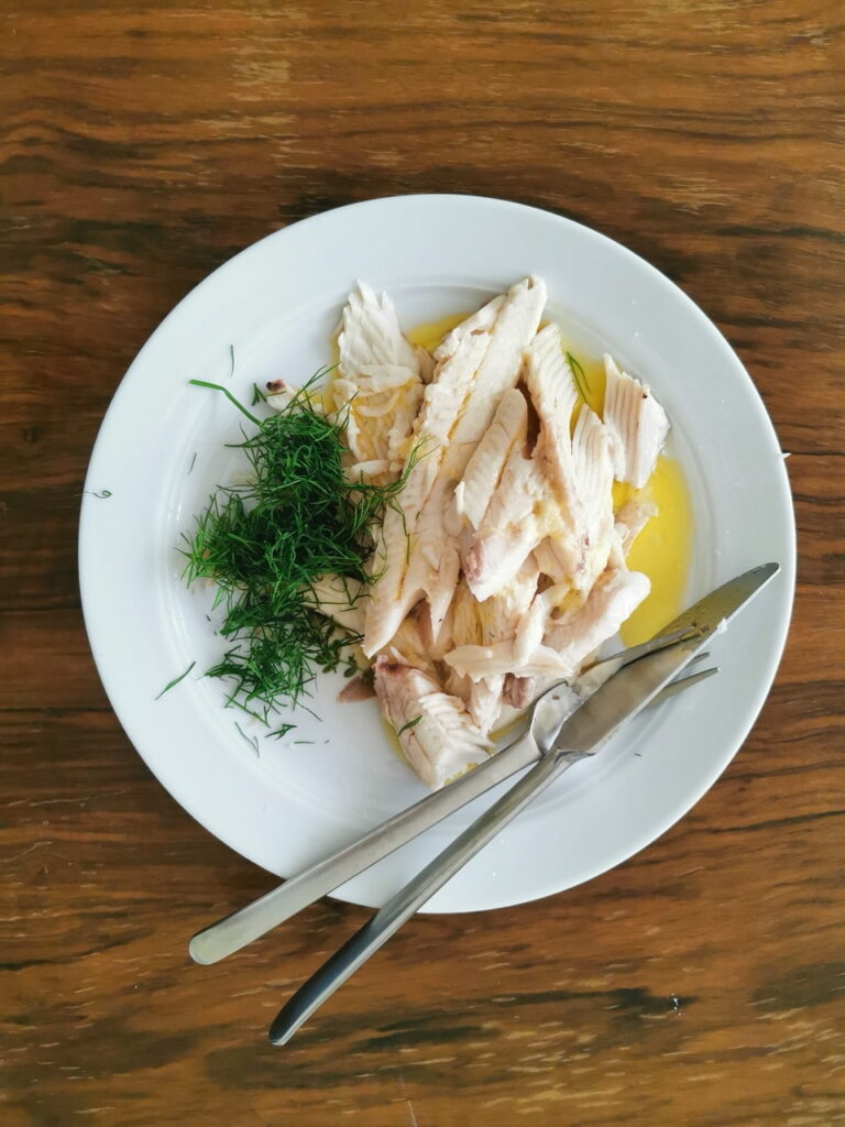 Forelle blau nach Sonja Kauf auf einem Teller mit Dill und zerlassener Butter serviert