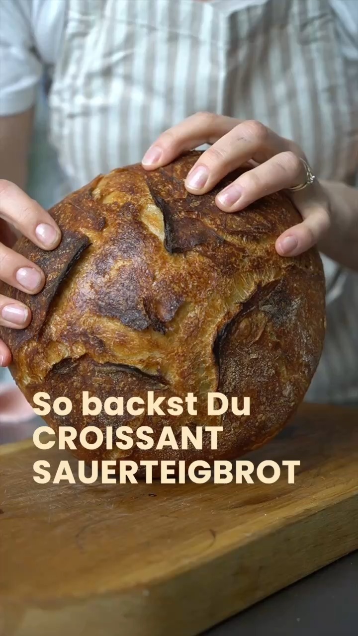 So backst Du das herrlichste Croissant-Sauerteigbrot der Welt.

Vorteig
30 g Weizenmehl (12% Proteingehalt)
30 g Vollkornweizenmehl
60 g Wasser
30 g reifer Sauerteig-Starter
Hauptteig
820 g Weizenmehl 
66 g Vollkornweizenmehl
670 g Wasser
17 g Salz
reifer Vorteig (Levain)
100 eiskalte Butter

Anleitung
Vorteig ansetzen 
In einem kleinen Behälter alle Zutaten für den Vorteig vermischen und bei 25°C für 5 Stunden ruhen lassen.

Autolyse 
In einer mittelgroßen Schüssel Weizenmehl, Vollkornweizenmehl und 650 g (!) Wasser verkneten. Schüssel abdecken + den Teig 2 Stunden ruhen lassen.

Hauptteig mischen
Zum Teig in der Schüssel 20 g Wasser (bei Bedarf weniger , falls der Teig zu feucht wird), 17 g Salz und den reifen Vorteig geben. Alle Zutaten mit den Fingern einarbeiten und den Teig durch wiederholtes Falten in der Schüssel für 2–3 Minuten glätten, bis er geschmeidig und zusammenhängend ist. Danach den Teig in eine Gärbox oder eine große Schüssel umfüllen und abdecken.

Stockgare 
Der Teig wird 6-mal gedehnt und gefaltet:
Die ersten drei Faltvorgänge im Abstand von 15 Minuten.
Die letzten drei Faltvorgänge im Abstand von 30 Minuten.

Teilen und vorformen 
Die Arbeitsfläche leicht bemehlen, den Teig aus der Schüssel holen und mit einer Teigkarte in zwei Hälften teilen. Jede Hälfte locker zu einer runden Form vorformen und 30 Minuten ohne Abdeckung ruhen lassen.

Laminieren
Teig dehnen und mit einer Reibe eiskalte Butter darüber raspeln.
Formen 
Den Teig zu einer runden Kugel Formen und in Gärkörbchen legen. Die Körbchen mit eine feuchten. Handtuch abdecken.

Endgare
Die abgedeckten Gärkörbchen in den Kühlschrank stellen und über Nacht reifen lassen.

Backen 
Den Ofen auf 230°C vorheizen. Idealerweise einen Gusseisentopf 30 min (Dutch Oven) aufheizen.

Den Teig aus dem Kühlschrank nehmen, einschneiden und in den heißen Topf legen.

Mit Deckel 20 Minuten backen.
Ohne Deckel weitere 30 Minuten backen.
Das Brot ist fertig, wenn die Kerntemperatur etwa 97°C beträgt.

Auf einem Gitter mindestens 2 Stunden auskühlen lassen, bevor es angeschnitten wird.

➡️ Speichere Dir das Rezept für Deinen nächsten Brunch ab.