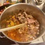 Knochen zum Gemüse hinzufügen, mit allen Flüssigkeiten auffüllen und langsam einkochen