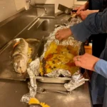 Der gegarte Wolfsbarsch wird aus der Alufolie genommen