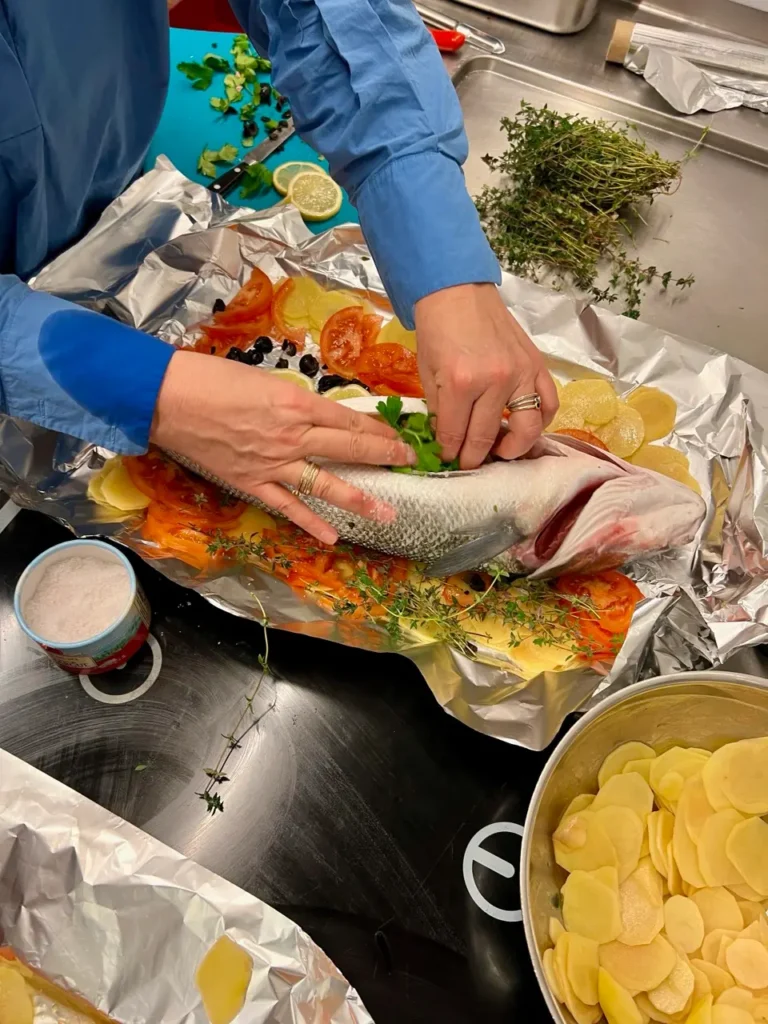 Wolfsbarsch wird auf dem Kartoffel-Tomaten-Bett und wird mit Petersilie und Thymian gefüllt