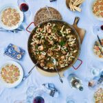 Fertige Paella auf Untersetzern auf einem Tisch für zwölf Personen