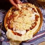 Geschichtete italienische Lasagne wird vor dem Backen mit geriebenem Parmesan bestreut