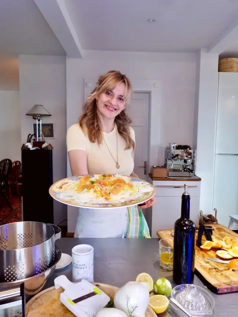 Vivi from Vivi kocht holds up a plate of fennel, orange and ginger salad and smiles