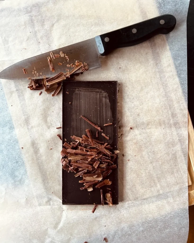 Mit einem Messer ausf einer Schokolade schaben, so entstehen Schokoladenstreussel