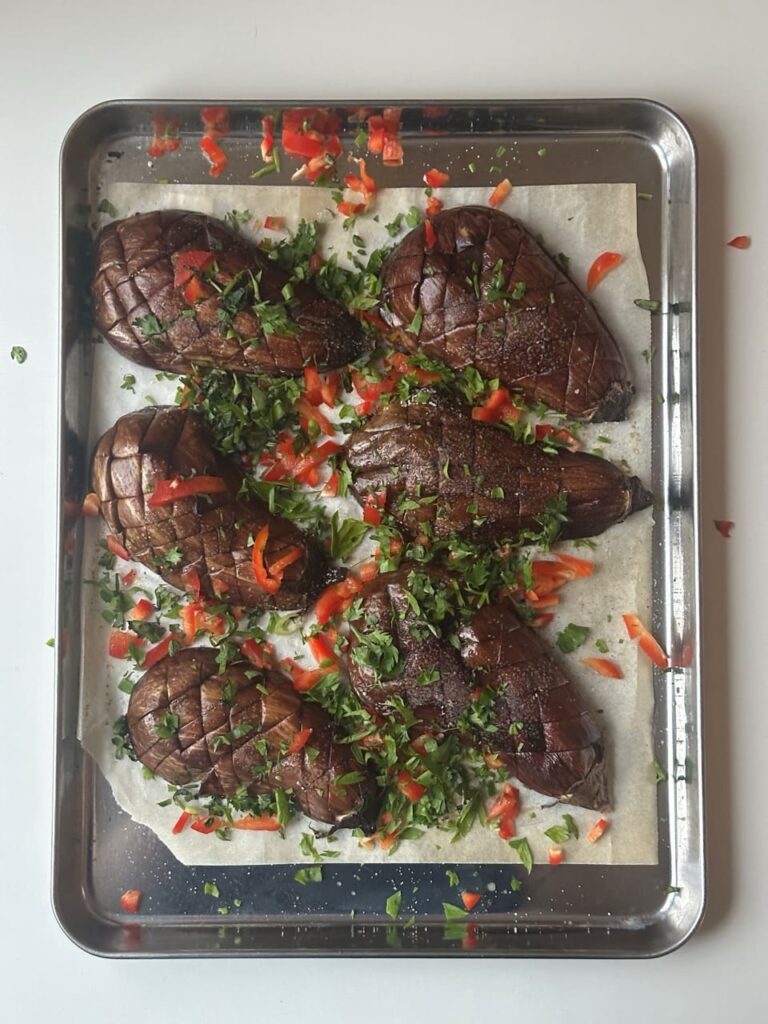 Ufen aubergine auf einem Blech gebacken, kreuzweise eingeschnitten, mit Ingwerkräutern und Paprika bestreut