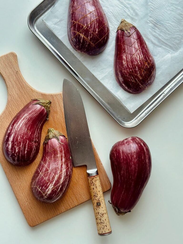 Ofenaubergine werden mit einem Messer kreuzweise eingeritzt.