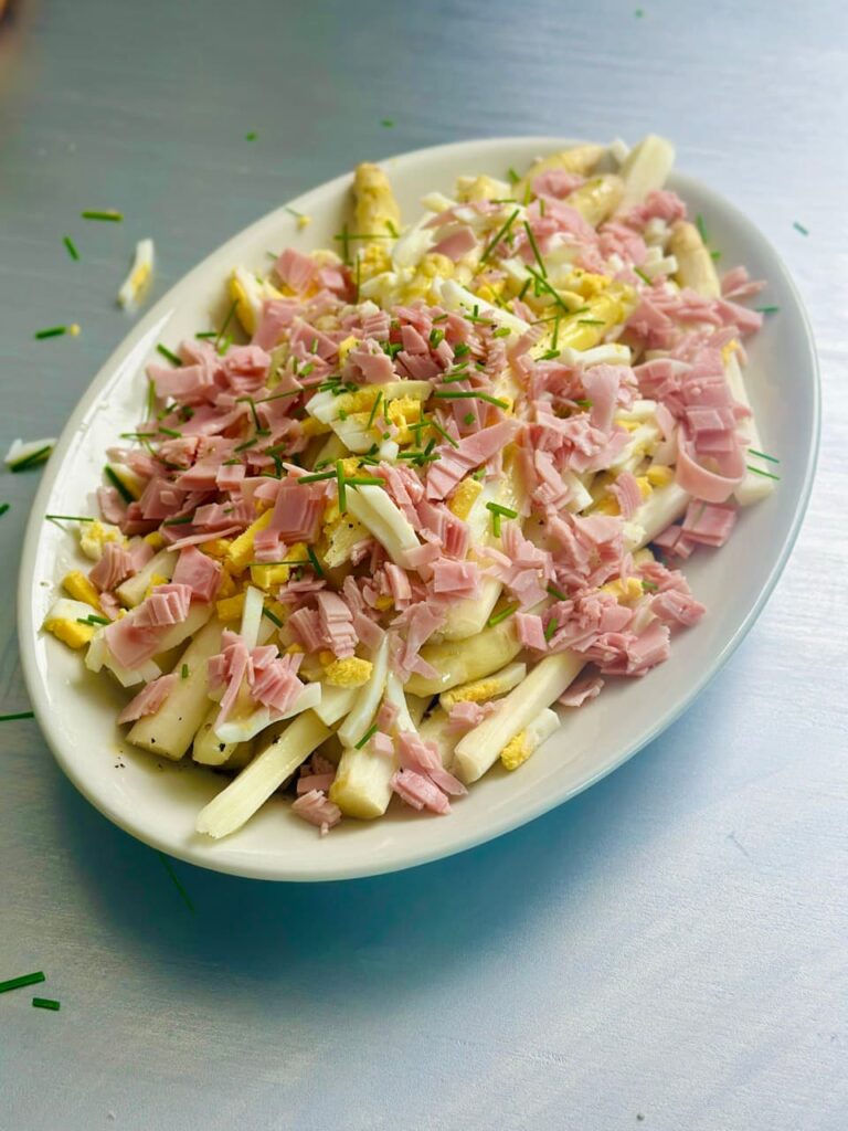 Asparagus salad with cooked ham, egg and chives on a plate