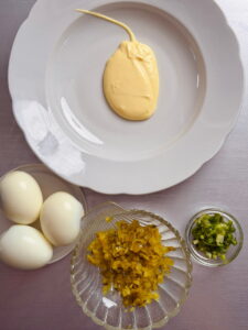 Alle Zutaten liegen auf einzelnen Tellern: - Eier - Gewürzgurken - Mayonnaise