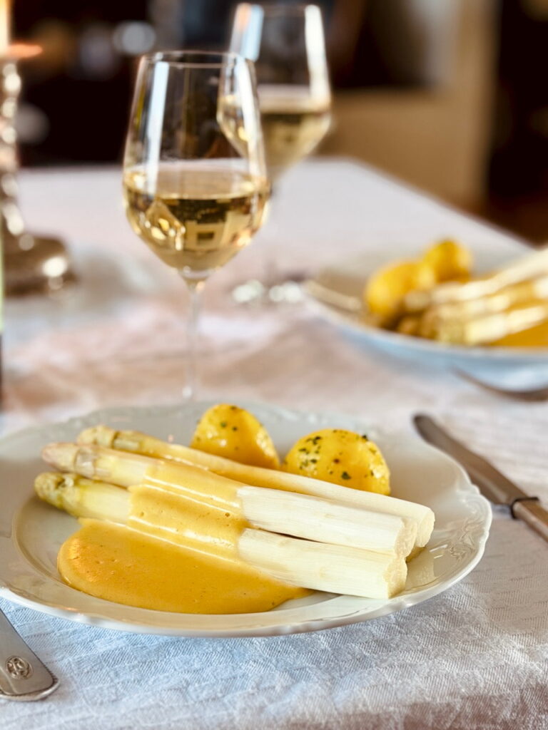 Sauce Hollandaise läuft über weissen Spargel auf einem Teller