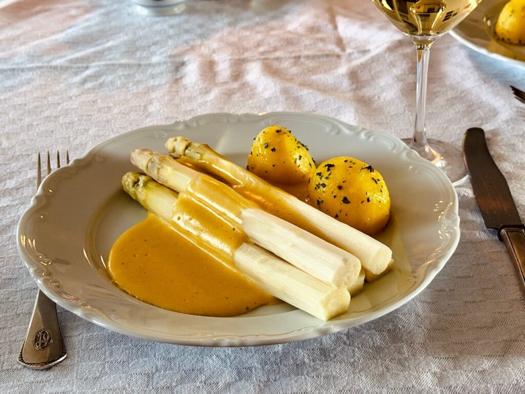Sauce Hollandaise läuft über weissen Spargel auf einem Teller