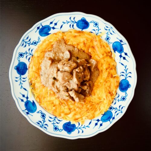 Zürcher Geschnetzeltes mit Rösti auf einem traditionellen blau-weissen Schweizer Teller