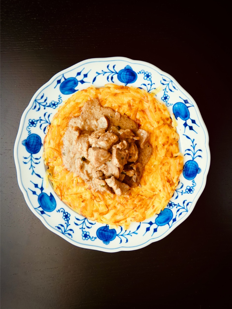 Zürcher Geschnetzeltes mit Rösti auf einem traditionellen blau-weissen Schweizer Teller