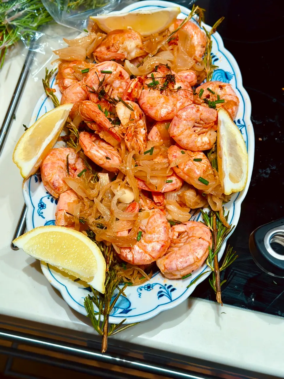 Geröstete argentinische Rotgarnelen mit Zwiebeln, Zitrone und Limette auf einem Teller, dazu Knoblauchmayonnaise